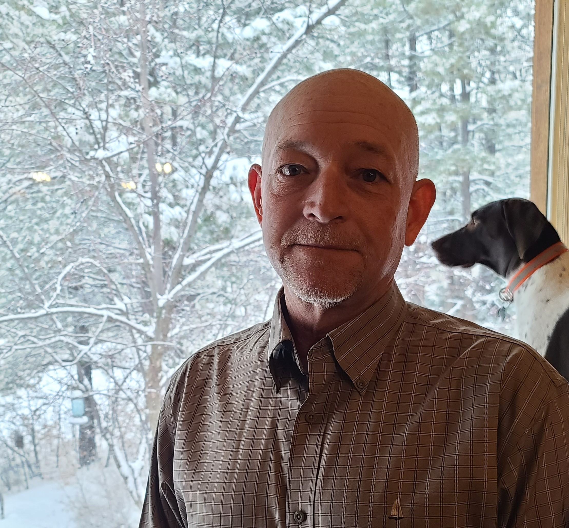 Board member David Pribble in front of a window with dog behind him.