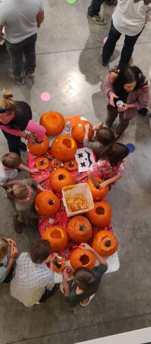 Overhead look at teachers and students carving pumpkins.