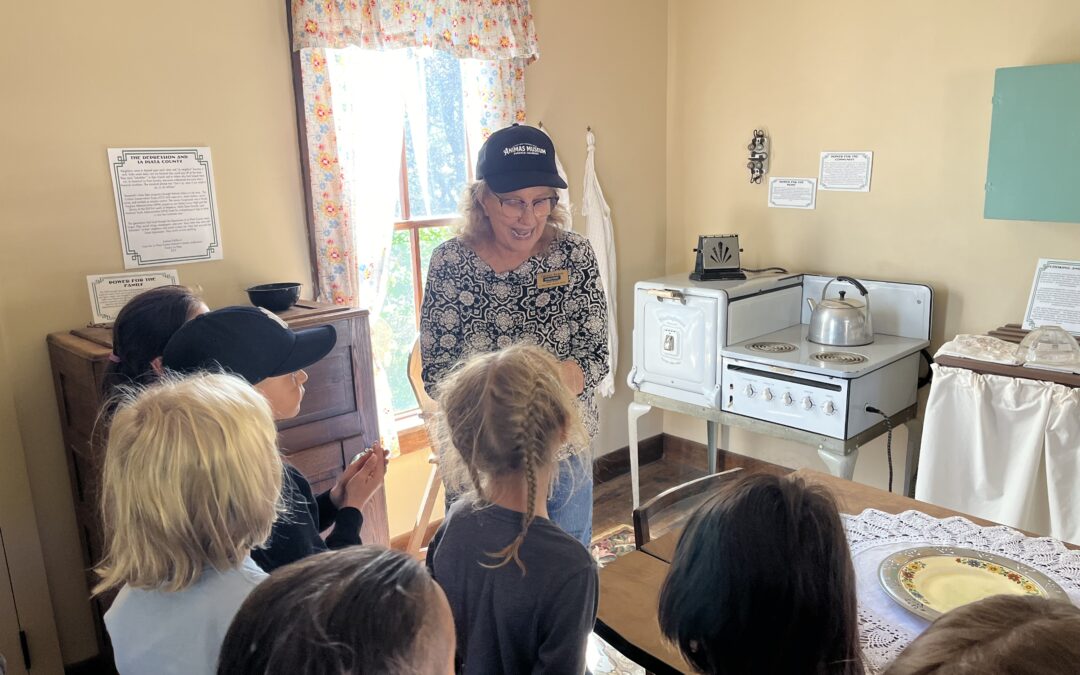 Group of PPOS second graders listening to a museum tour guide standing in a recreation of a 1930s kitchen