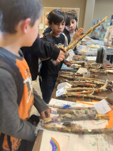 Four PPOS students at a table working on a project with sticks