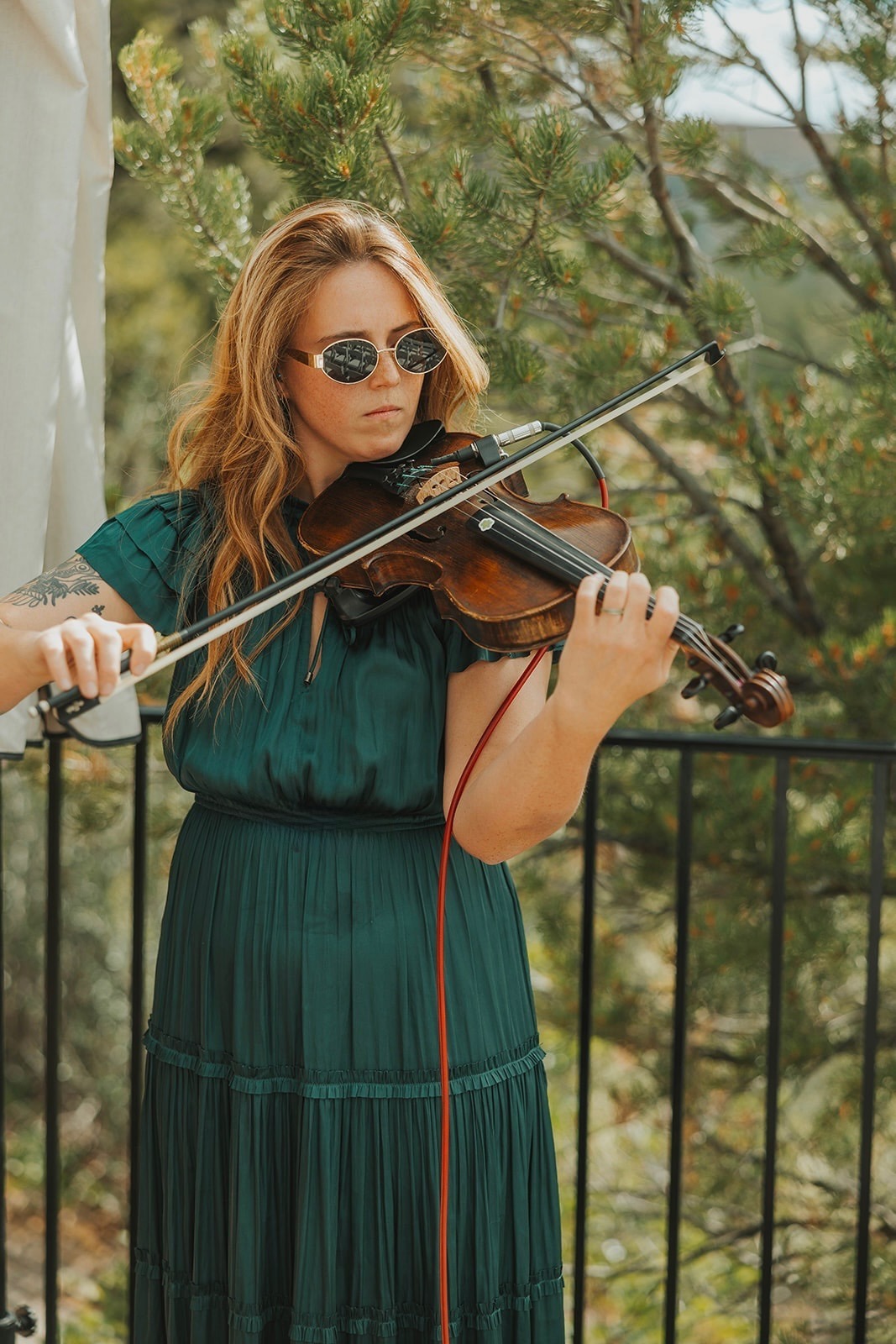 Payton McIntyre standing on a balcony playing the violin